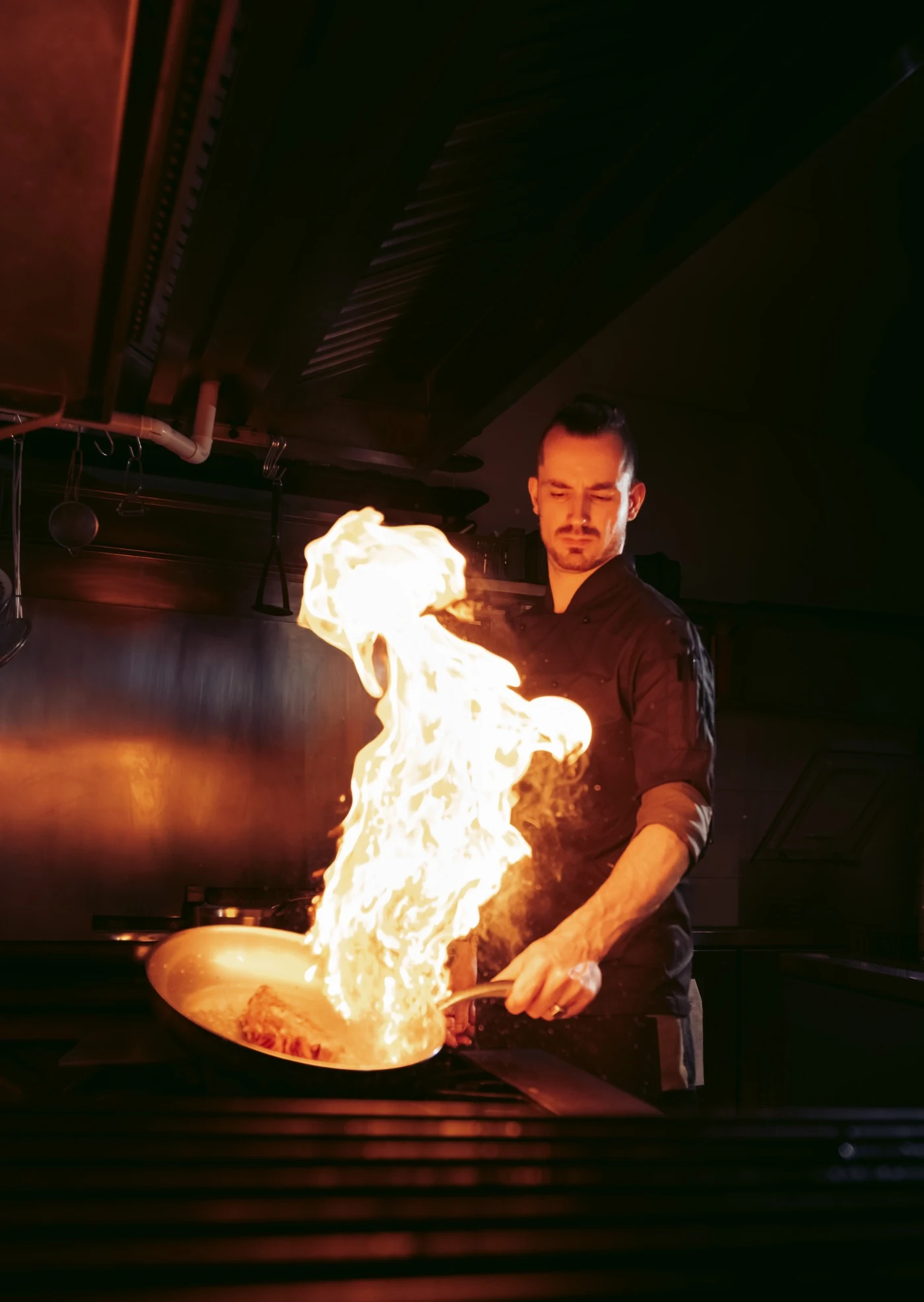 Chef Simon Guitard preparando um prato na cozinha do Beau Social Club